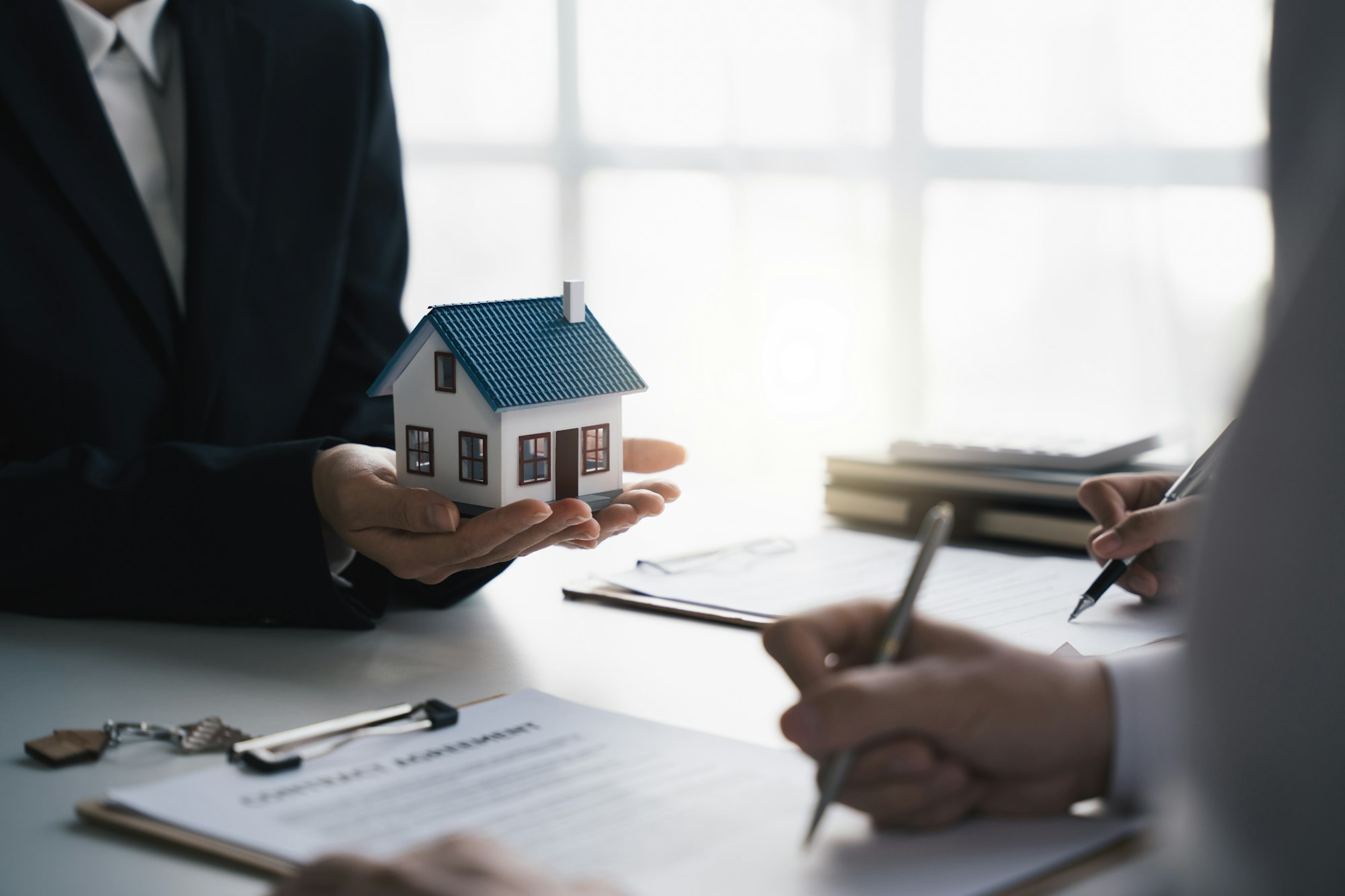 Close-up of real estate agent give home model to customers, new homeowner signing of contract agreem